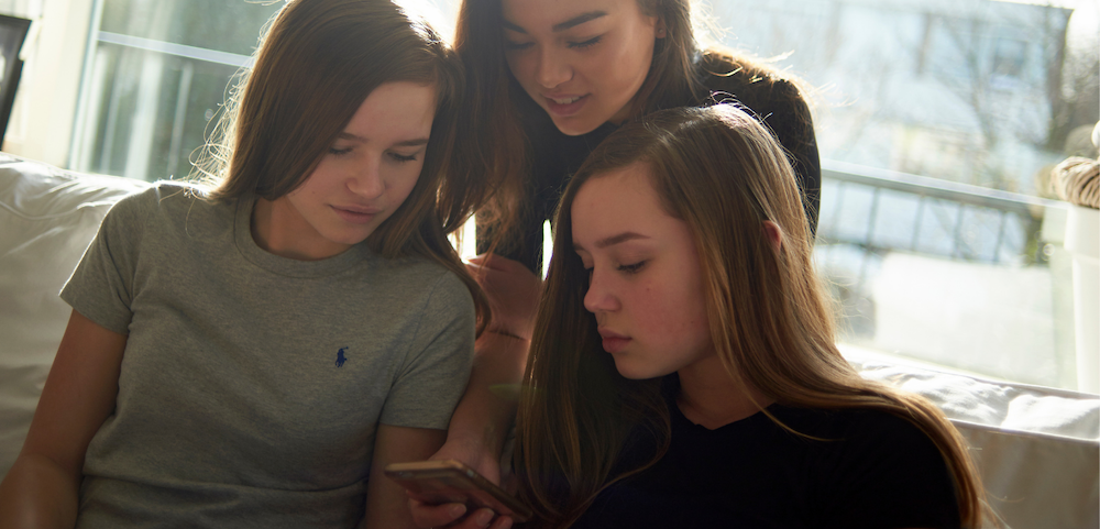 Teen girls looking at phone together